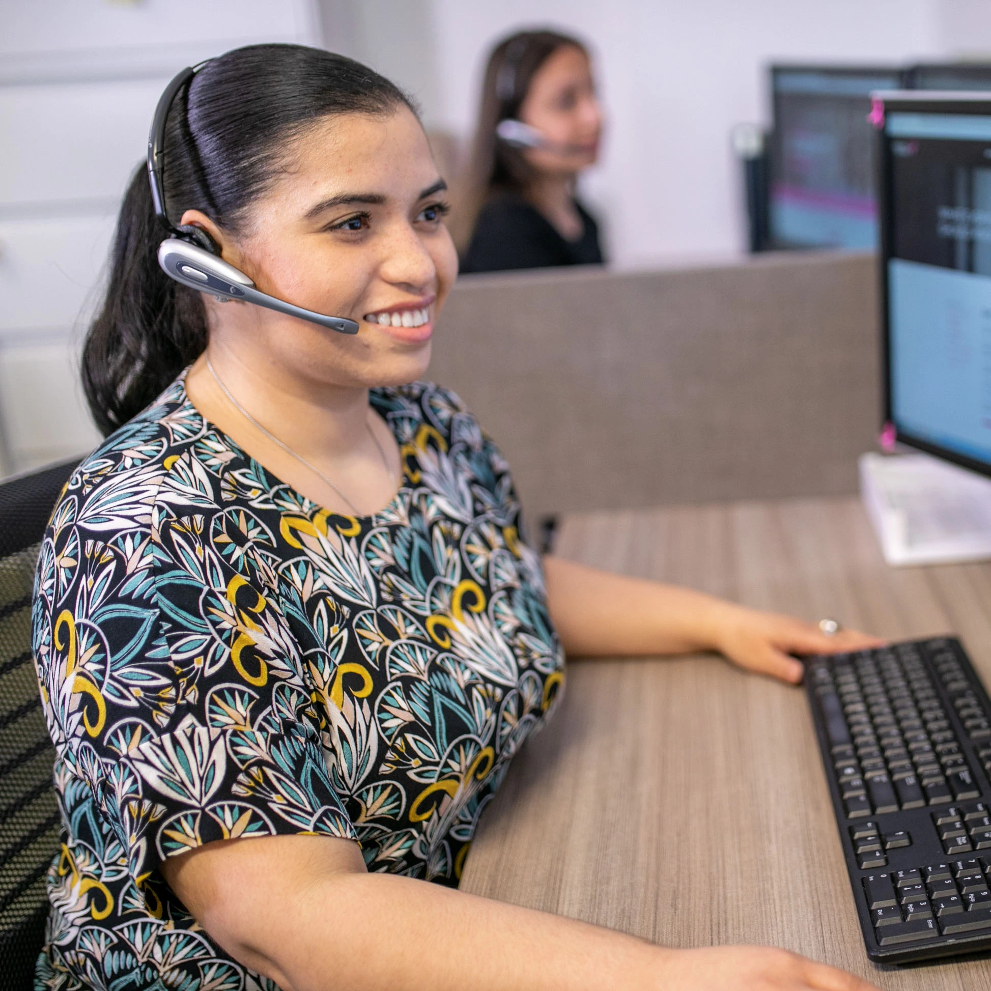 Photo of a young woman with a headset at a computer