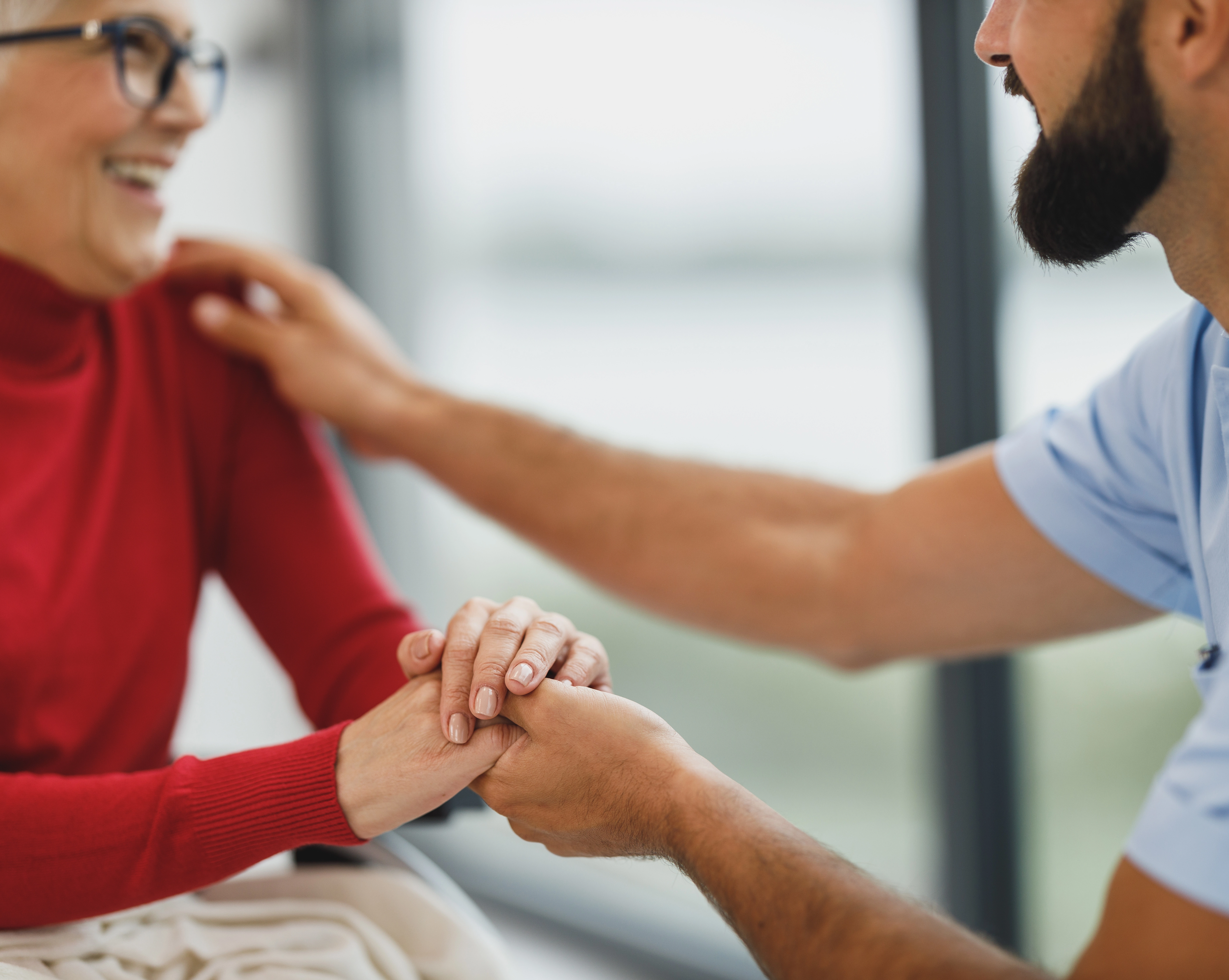 Photo of an older woman holding hands with a health care professional